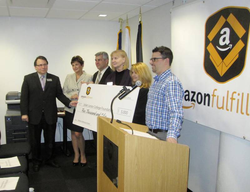 Mike Flannery (far right), general manager at the Amazon Fulfillment Center in Joliet, presents a mock check Wednesday to Joliet Junior College with Peter Linden (from left), dean of career and technical education; Judy DeVriendt, president of the Joliet Junior College Foundation Board; Joliet Mayor Bob O'Dekirk; JJC President Deb Daniels; and Joliet Councilwoman Jan Quillman.