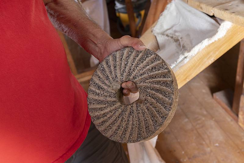 The 2,600-pound grinding wheel is made of blue basalt. Russell displays a small sample Friday, June 7, 2024.