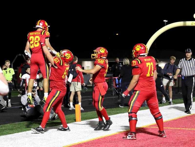 Batavia’s Bradyn Martinson (right) lifts up teammate Nathan Whitwell after Whitwell scored a touchdown on Friday, Oct. 18, 2024 during a game against Wheaton Warrenville South in Batavia.