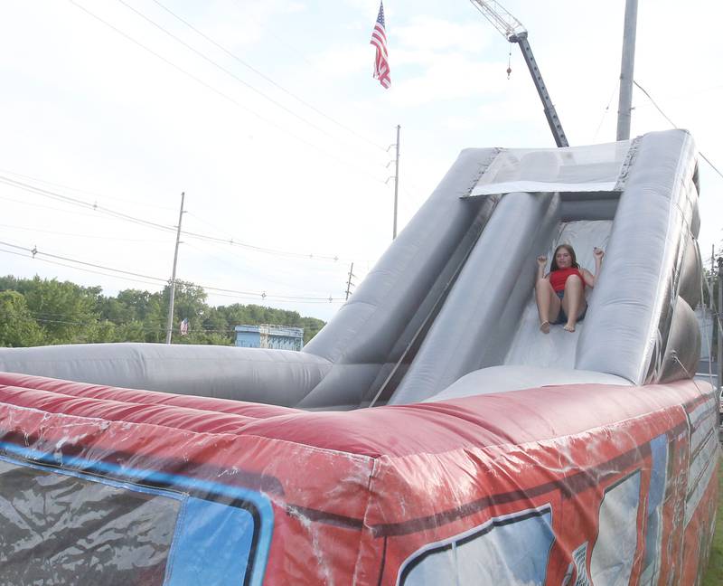 Emma Treest of Ottawa, slides down a firetruck bounce house before the fireworks on Wednesday, July 3, 2024 along Water Street in Peru.