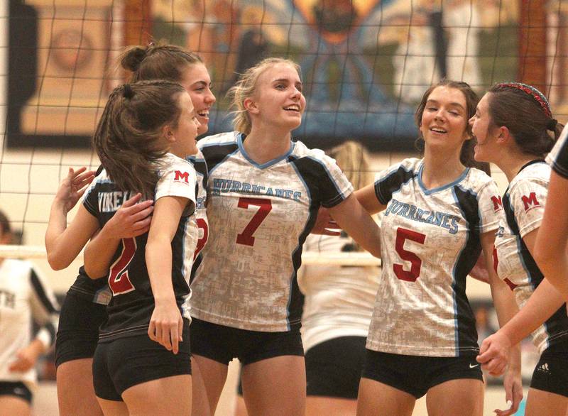 Marian Central’s Jordan Orlos (7), Caroline Stumpf (5),  and the Hurricanes celebrate a point against Grayslake North in girls volleyball in Woodstock Monday.