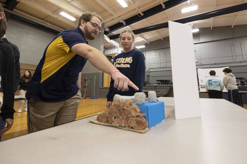 Sterling Challand Middle School eighth grade science and STEM teacher Jim Shamp point to sixth grader Kylie Shank’s Hoover Dam model during a STEM exhibit Thursday, March 9, 2023. Shank discovered that 7 million tourists a year visit the landmark, including a trip recently with her family.