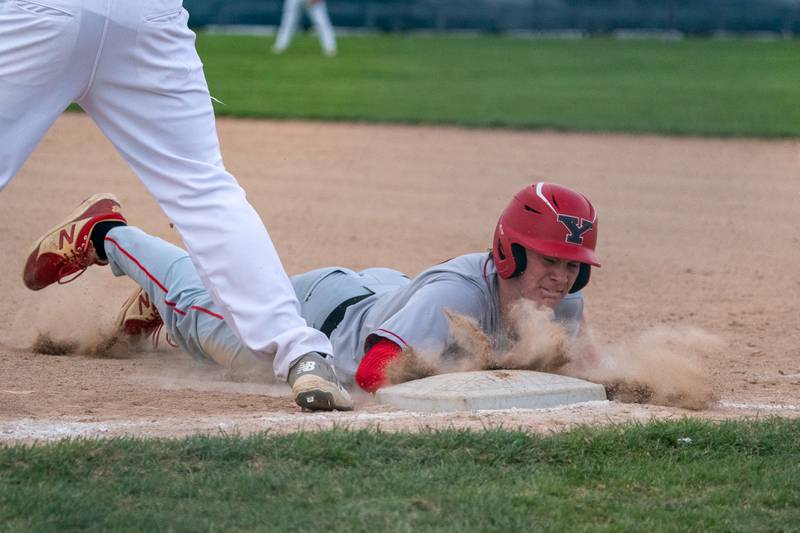 Yorkville's Nate Harris (15) dives back to first to avoid a pick-off attempt by West Aurora during a baseball game at West Aurora High School on Monday, April 24, 2023.