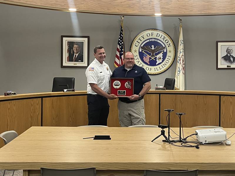 Chief Ryan Buskohl (left), of the Dixon City Fire Department, presented Deputy Chief David Lohse (right) with framed firefighter memorabilia in honor of his retirement, May 10, at the Dixon City Council meeting, Monday.
