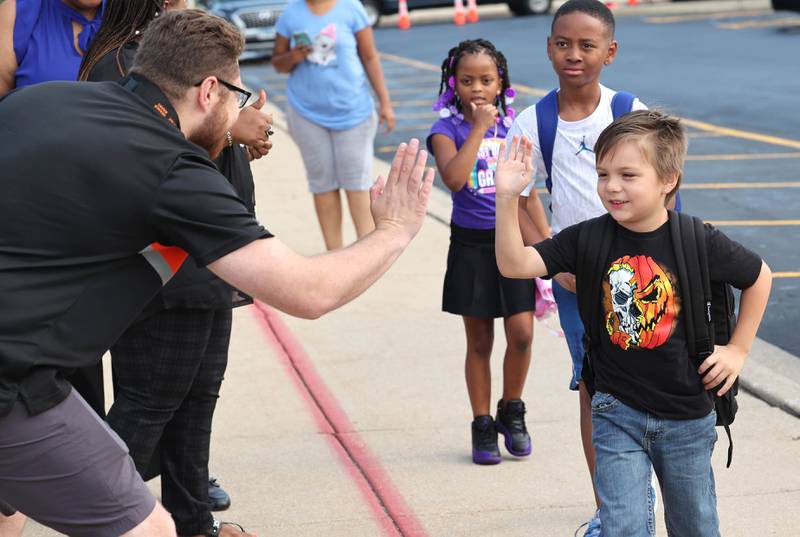 DeKalb School District 428 board member Christopher Boyes high fives students Thursday, Aug. 17, 2023, as they arrive for the first day of the new school year at Gwendolyn Brooks Elementary School in DeKalb.