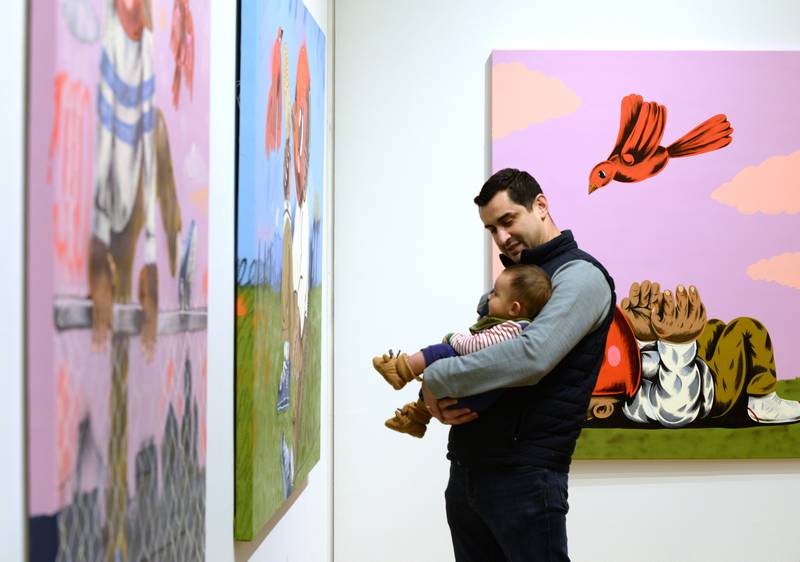 Rick Nevarez of Elmhurst watches his son Benjamin react to the colors of  Street Artist Sentrock (Joseph Perez of Chicago) "The Boy who Wanted to Fly" exhibit while also attending the Family Holiday Party at the Elmhurst Art Museum Saturday Dec 17, 2022.