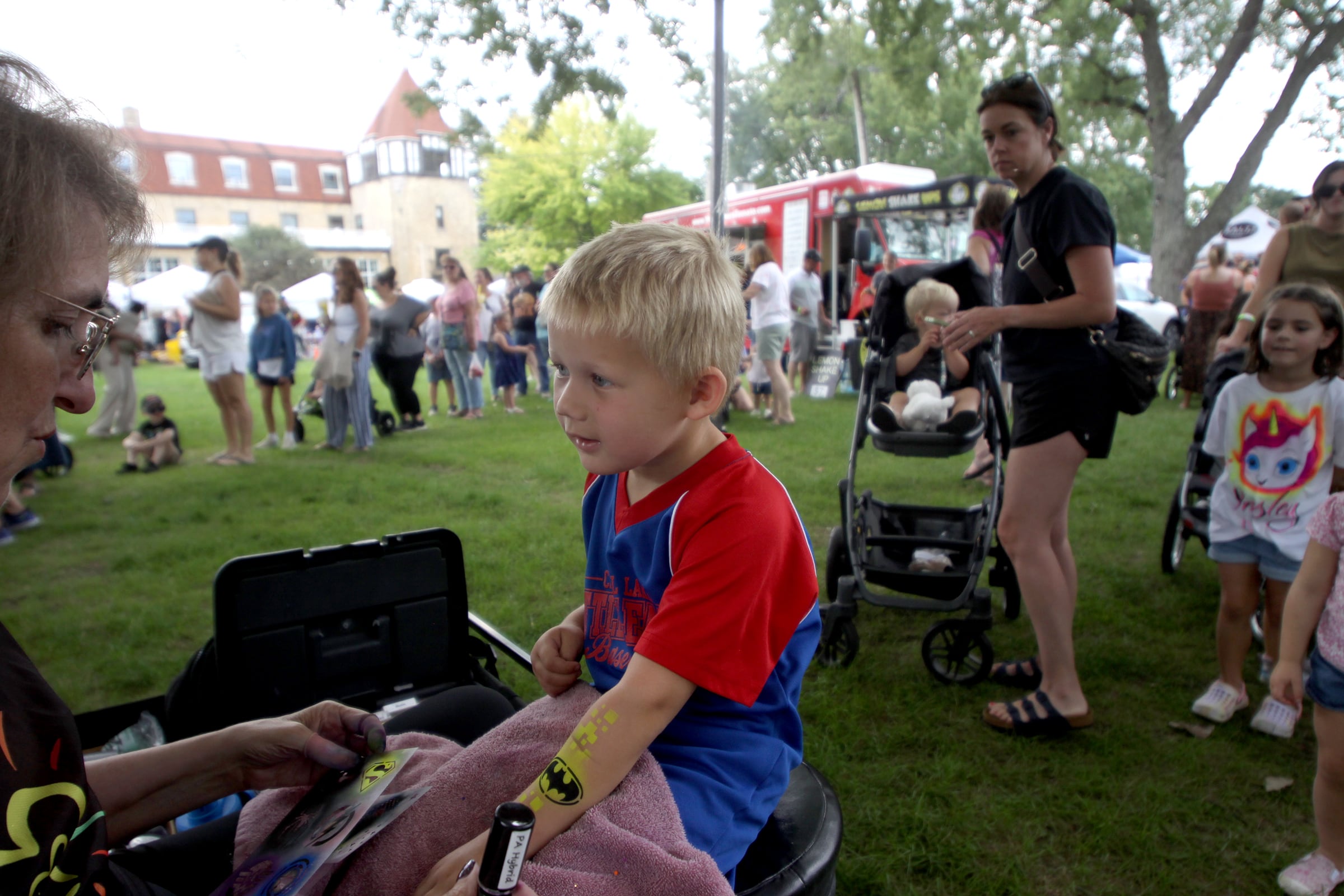 Bennett Anderson, 4, of Lake in the Hills has a superhero-themed design painted on his arm as part of The Dole Farmers Market in Crystal Lake Sunday.