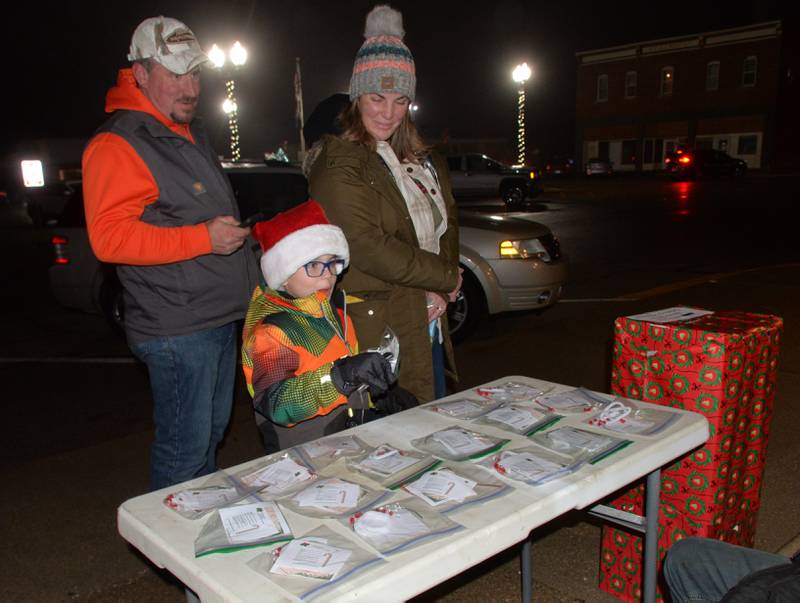 Bennett Drehmann, 8, of Erie, picks up an ornament kit with his mom and dad, Becky and Devin, while visiting the Erie Ministerial Benevolence table during Erie's Hometown Holidays on Saturday, Dec. 2, 2023.