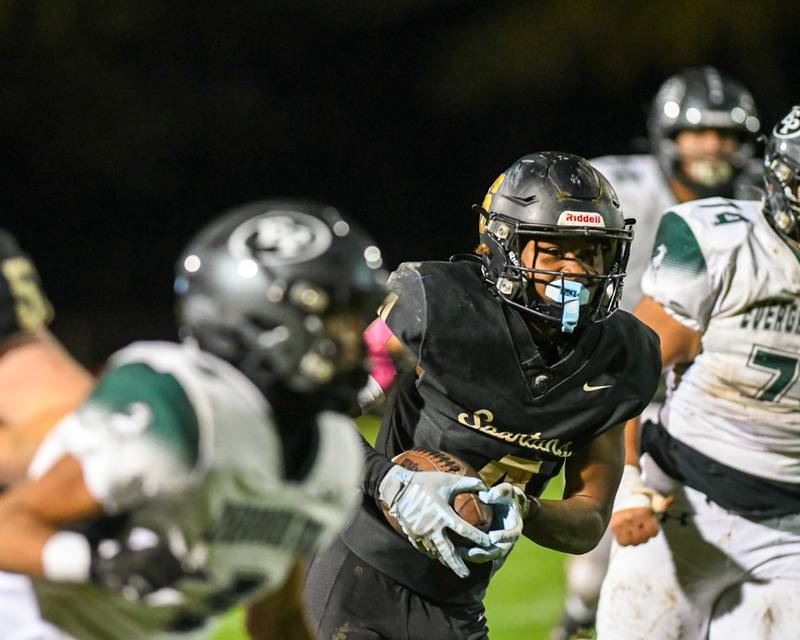 Sycamore Tyler Curtis (4) runs the ball after completing a pass on Friday Oct. 27, 2023, while being defended by Evergreen Park in the first week of play offs held at Sycamore High School.